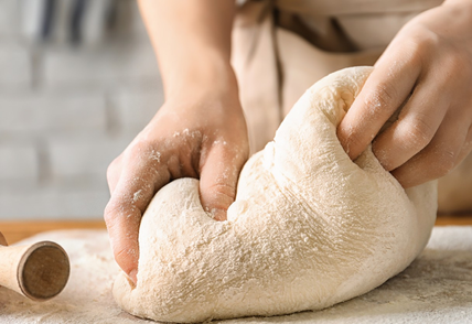 Woman kneading dough on board sprinkled with flour